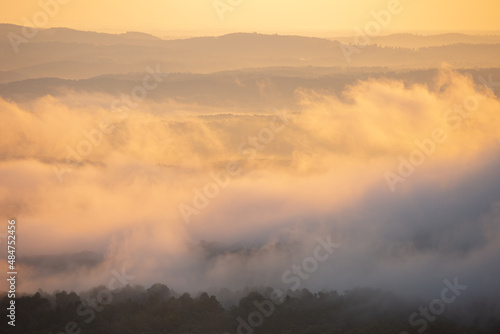 Foggy cloudy mist with sunrise glow over Grand Canyon mountains in Arkansas