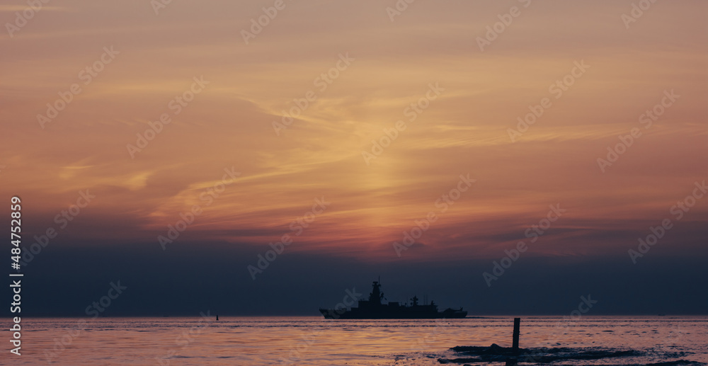sunset over the sea with navy ship