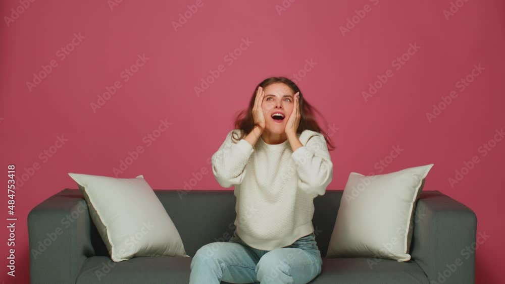 Happy exited young girl fan rejoice success win, feel euphoric, shouting, raising hands, sitting on sofa Happy exited young girl fan rejoice success win, feel euphoric, shouting, raising hands, sitting on sofa