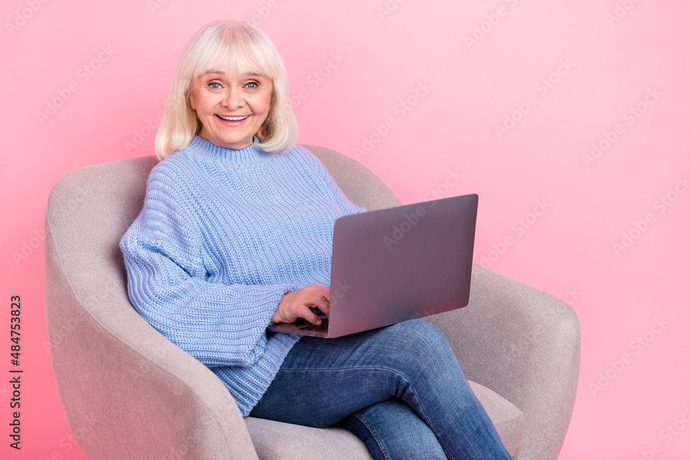 Naklejka premium Portrait of attractive cheerful grey-haired woman using laptop watching movie film isolated over pink pastel color background