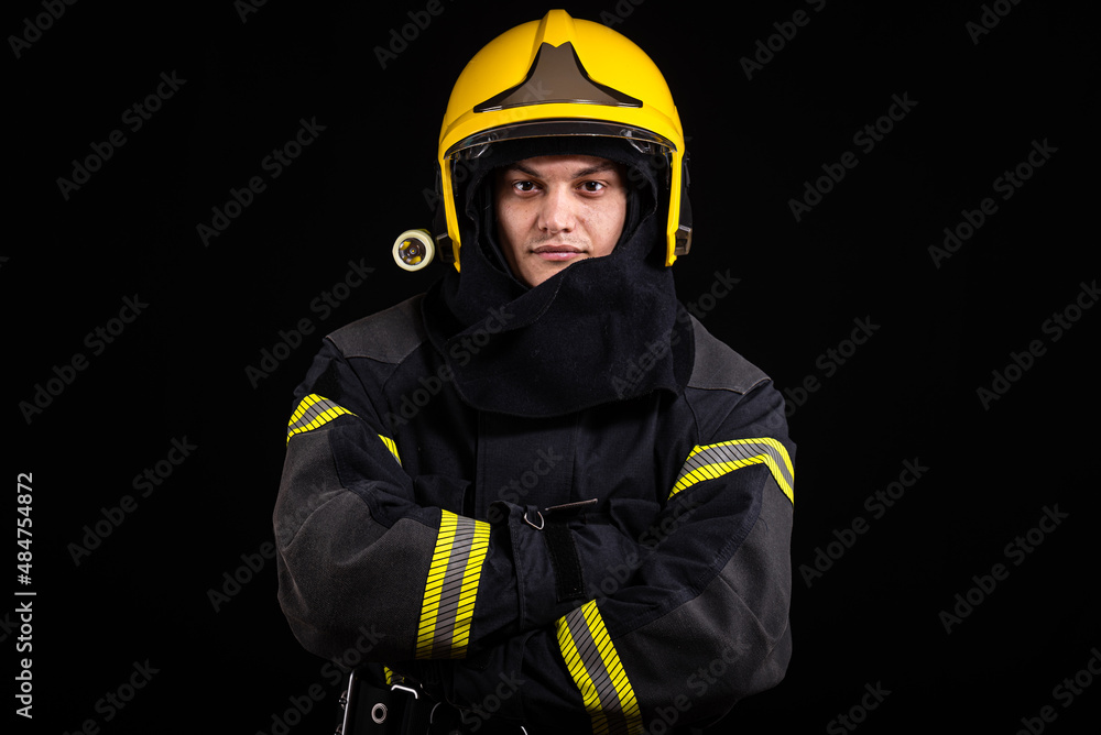 Fototapeta premium Firefighter fully equipped with helmet and ax in smoke, black background