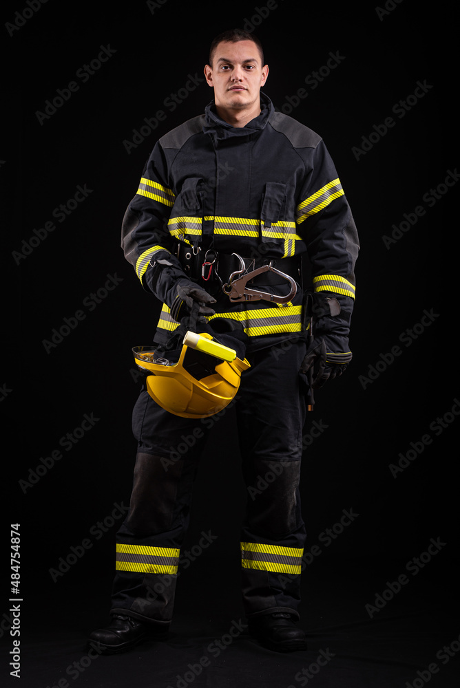 Firefighter fully equipped with helmet and ax in smoke, black background Firefighter fully equipped with helmet and ax in smoke, black background