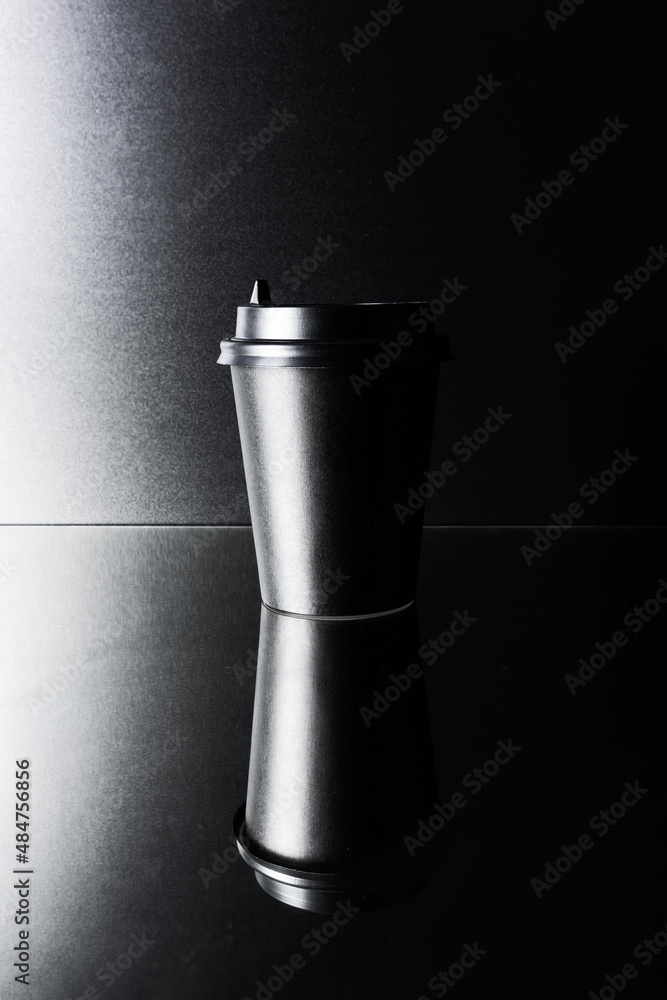Black paper glass, disposable takeout drink cup on black mirror surface Black paper glass, disposable takeout drink cup on black mirror surface