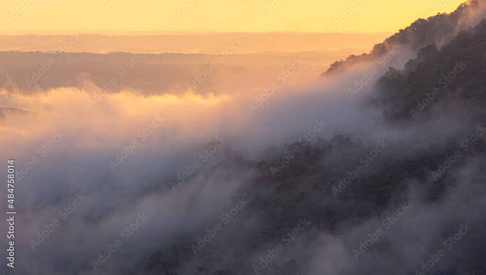 Foggy cloudy mist with sunrise glow over Grand Canyon mountains in Arkansas Foggy cloudy mist with sunrise glow over Grand Canyon mountains in Arkansas