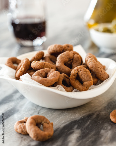 Taralli with red wine in a white bowl on a marble table. Vegan aperitif. Savory snack