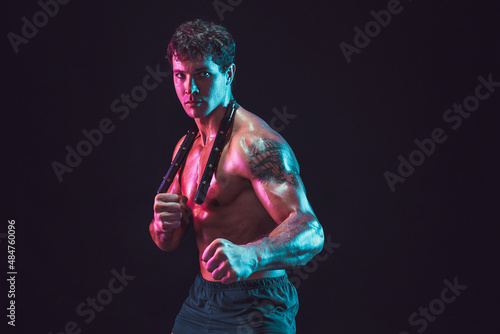 Studio shot of Strong male athlete who posing with nunchaku on black background. Sport concept  photo
