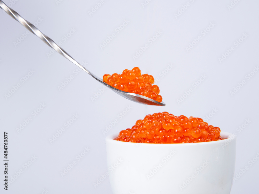 Red caviar in silver spoon isolated on the white background Red caviar in silver spoon isolated on the white background