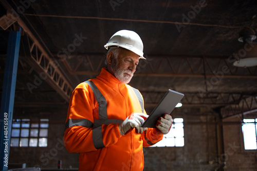 Valokuvatapetti Professional senior heavy industry engineer worker wearing safety uniform and hard hat, using tablet computer controlling production