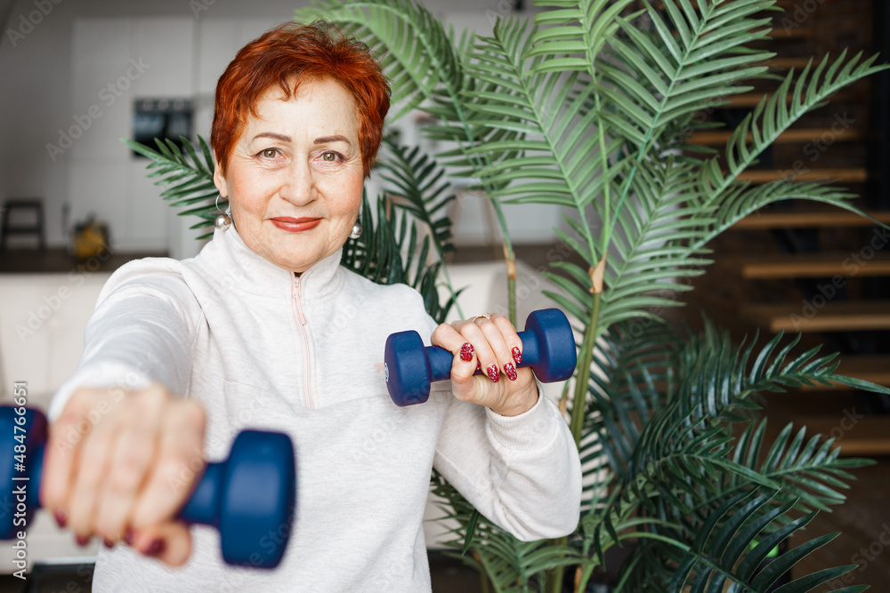 Older Caucasian woman works out with dumbbells at home Older Caucasian woman works out with dumbbells at home