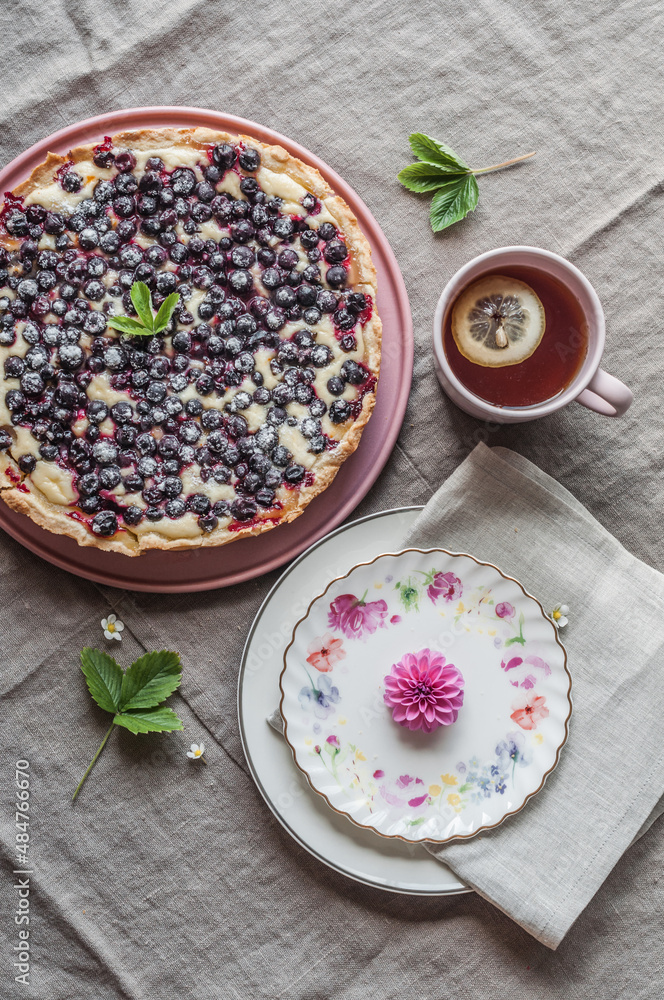 Black currant pie, a cup of lemon tea and plates with dahlia flower. Black currant pie, a cup of lemon tea and plates with dahlia flower.