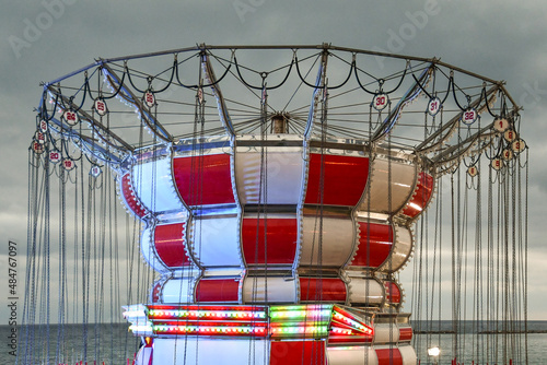 High-section of a swing ride on the waterfront against cloudy sky and sea at dusk, Sanremo, Imperia, Liguria, Italy