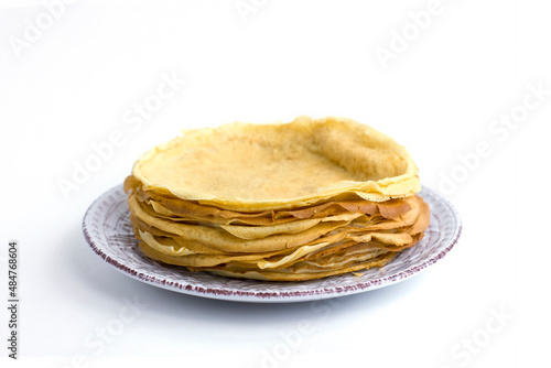 Thin pancakes stacked on a plate isolated on white background.