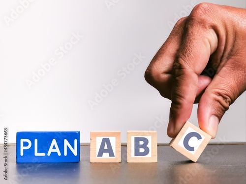 Business plan concept. Plan A, B and C on wooden cubes with hand.