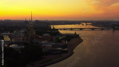 Drone flight over the Neva River to the Peter and Paul Fortress at sunrise, reflection of the orange sky on the water, drawbridges Troitsky and Liteiny are separated,  photo