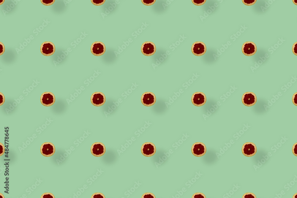Colorful fruit pattern of fresh grapefruits on green background with shadows. Top view. Flat lay. Pop art design Colorful fruit pattern of fresh grapefruits on green background with shadows. Top view. Flat lay. Pop art design