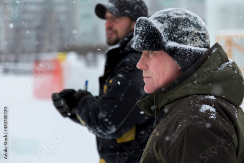 Workers in winter overalls walk along the construction site