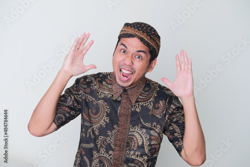 Adult Asian man wearing Javanese costume screaming loud showing stressed expression