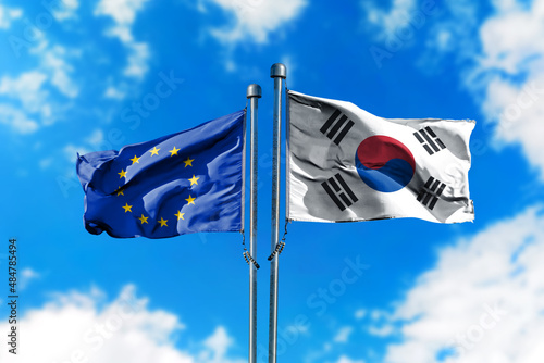 Flags of European Union and South Korea on the wind against blue sky
