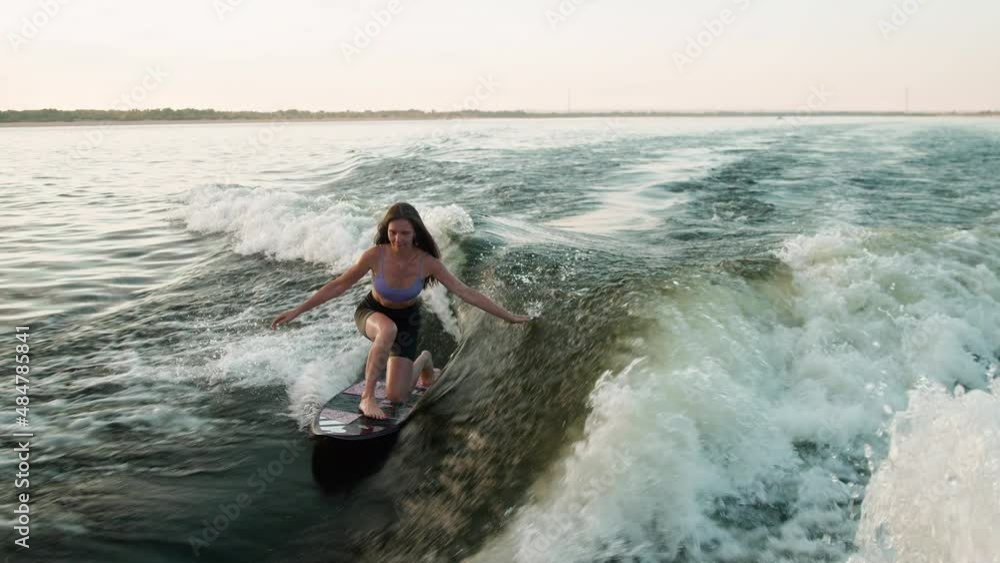 A female surfer jumping on a wakeboard. An experienced wakeboarder splashes water drops into the camera. A female surfer jumping on a wakeboard. An experienced wakeboarder splashes water drops into the camera.