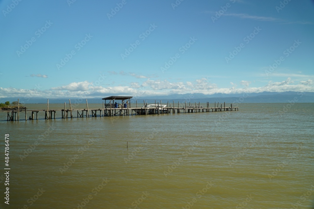 Wooden bridge by the sea, clear water and blue sky.
