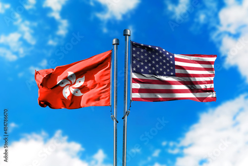 Flags of Hong Kong and America on the wind against blue sky
