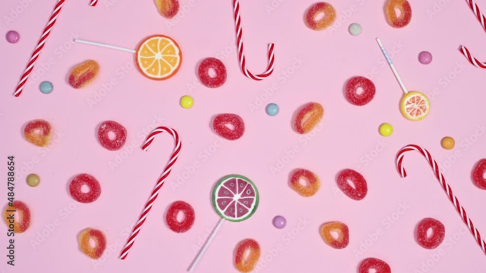 Lollypops, candies and gummy candies filling pastel pink background and making pattern. Stop motion animation flat lay Lollypops, candies and gummy candies filling pastel pink background and making pattern. Stop motion animation flat lay