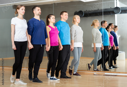Group of adult people lining up while fulfilling dance movements of folk Celtic dance in choreography class