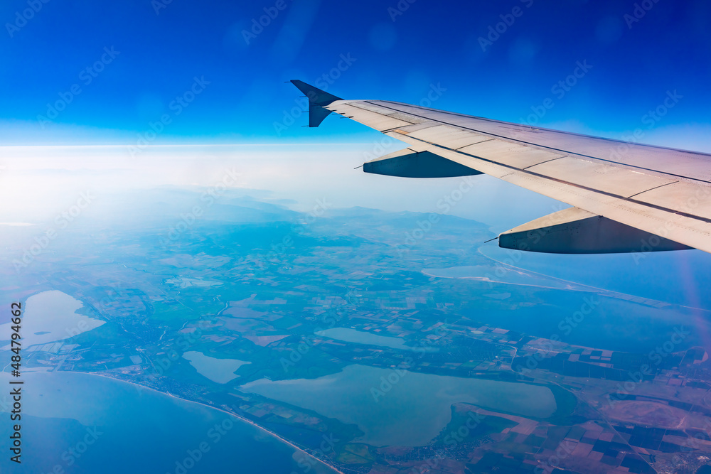 View from the airplane window at a beautiful blue clear sky, earth, sea and the airplane wing View from the airplane window at a beautiful blue clear sky, earth, sea and the airplane wing