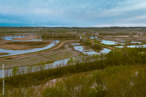 High angle view of Missouri River floodplain with water and plowed agricultural fields;  distant forest and blue sky in background; spring in Midwest photo