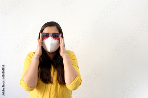 Latin adult woman with face mask and heart-shaped glasses excited for February Valentine s Day of Love and Friendship in the new normality due to the Covid-19 pandemic 