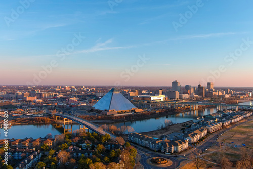 a stunning aerial shot of the the buildings in the cityscape along Wolf River Harbor with a glass pyramid and vast miles of buildings with powerful clouds at sunset at Greenbelt Park on Mud Island