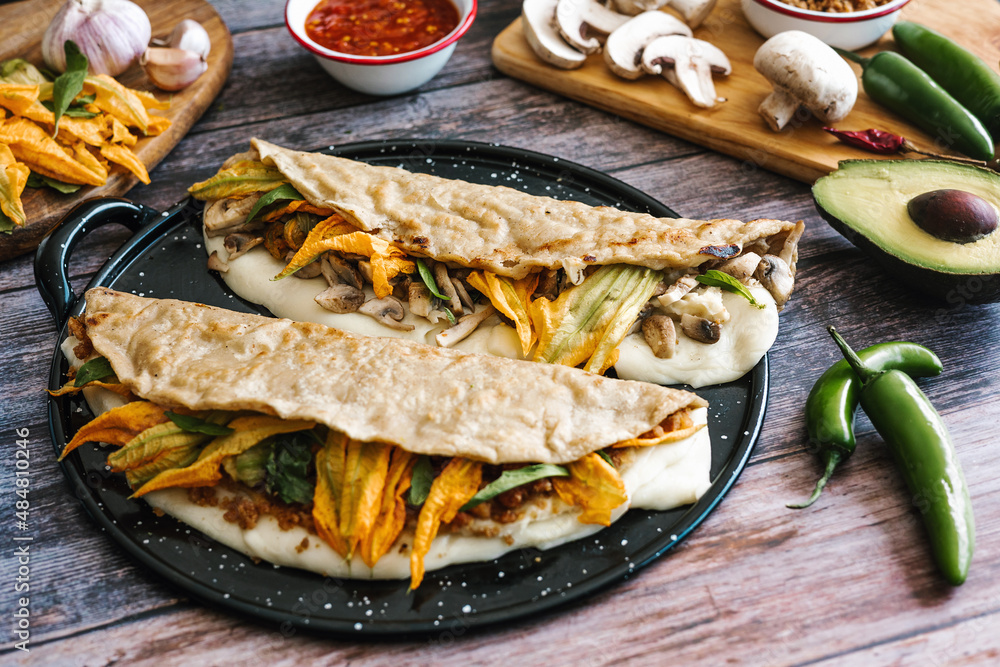 Mexican chicharrón quesadilla with oaxaca cheese and squash blossom, traditional food from the city of Puebla in Mexico Mexican chicharrón quesadilla with oaxaca cheese and squash blossom, traditional food from the city of Puebla in Mexico