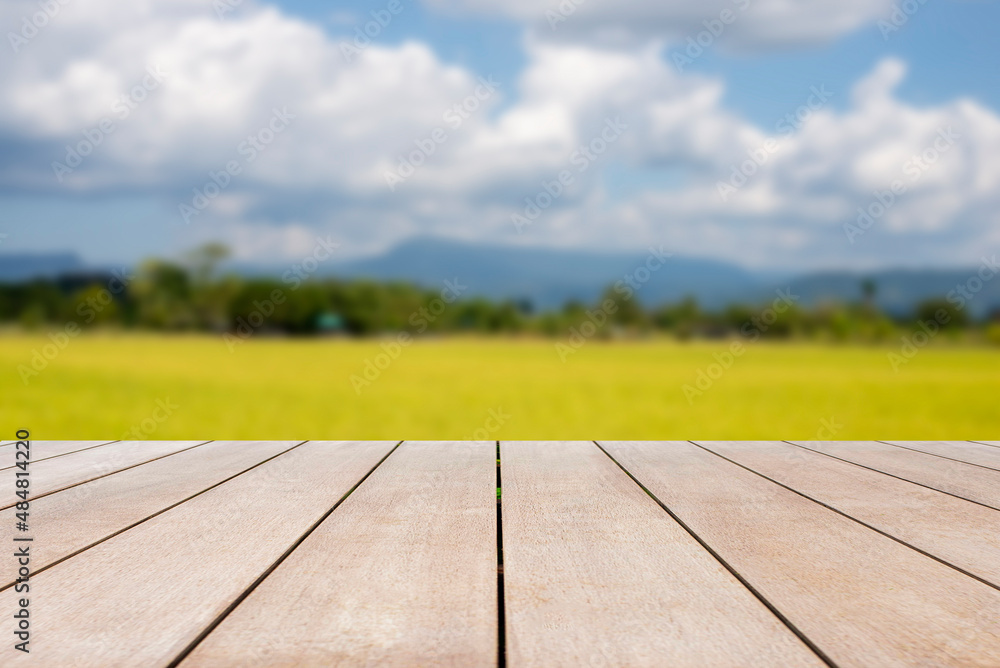 Empty old wooden table in front of blurred beautiful view organic rice field, mountain, tree, cloud and blue sky on clear day in country. Can be used for display or montage for show your product.