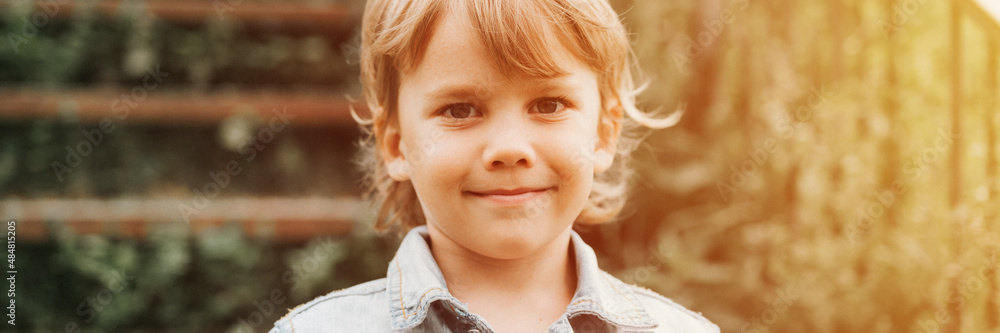 portrait of face of a cute happy smiling little five year old dishevelled long blond caucasian preschool or homeschooler kid boy on nature close up. careful childhood of children. banner. flare portrait of face of a cute happy smiling little five year old dishevelled long blond caucasian preschool or homeschooler kid boy on nature close up. careful childhood of children. banner. flare