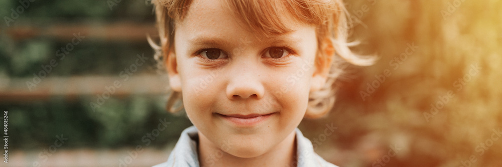 portrait of face of a cute happy smiling little five year old dishevelled long blond caucasian preschool or homeschooler kid boy on nature close up. careful childhood of children. banner. flare portrait of face of a cute happy smiling little five year old dishevelled long blond caucasian preschool or homeschooler kid boy on nature close up. careful childhood of children. banner. flare