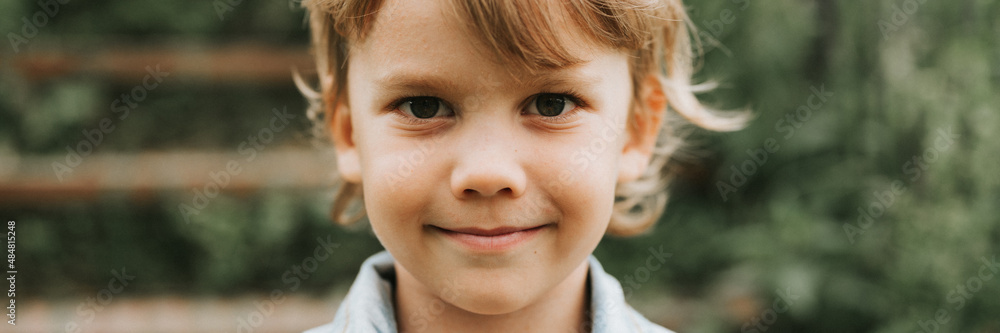 portrait of face of a cute happy smiling little five year old dishevelled long blond caucasian preschool or homeschooler kid boy on nature close up. careful childhood of children. banner portrait of face of a cute happy smiling little five year old dishevelled long blond caucasian preschool or homeschooler kid boy on nature close up. careful childhood of children. banner