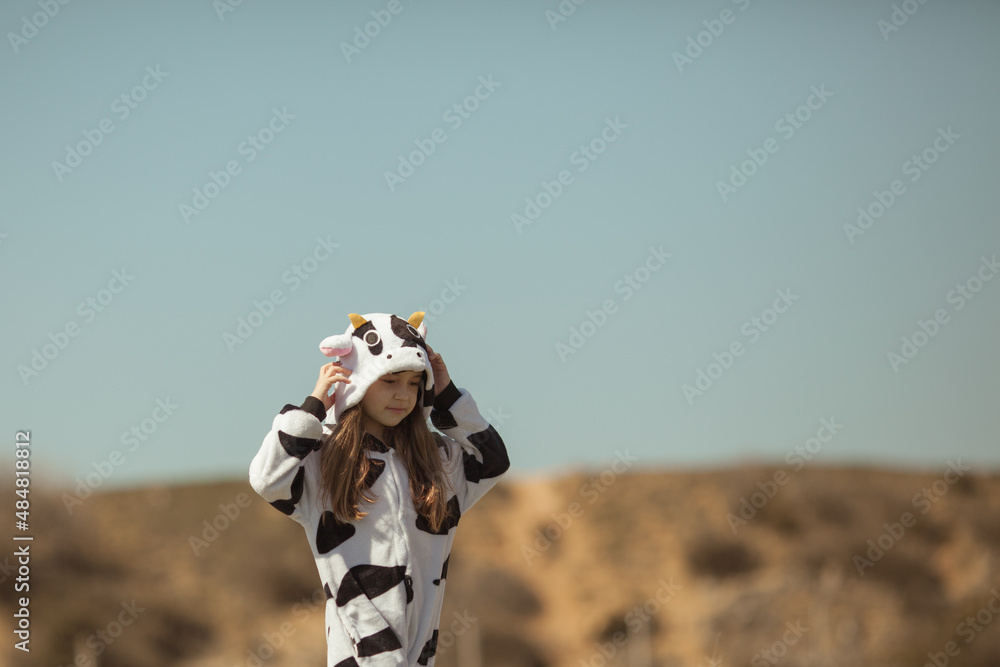 Happy girl in kigurumi cow walks on the seashore on a spring day Happy girl in kigurumi cow walks on the seashore on a spring day