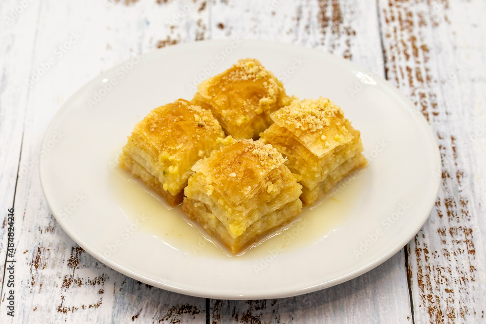 Baklava with milk (sutlu nuriye). Baklava with hazelnut and milk on a white wooden background.