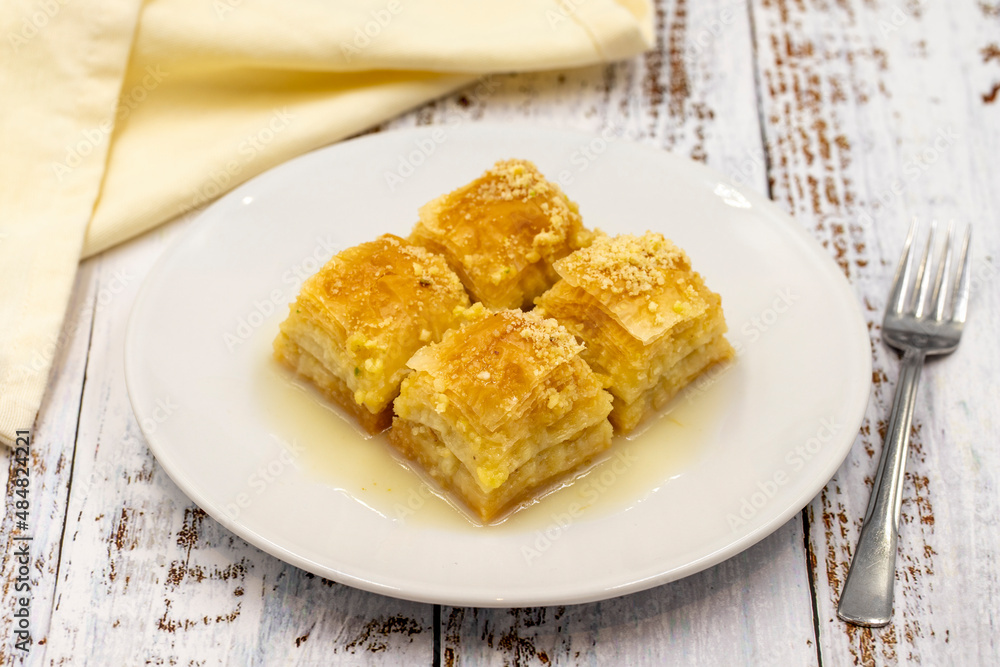 Baklava with milk (sutlu nuriye). Baklava with hazelnut and milk on a white wooden background. Baklava with milk (sutlu nuriye). Baklava with hazelnut and milk on a white wooden background.