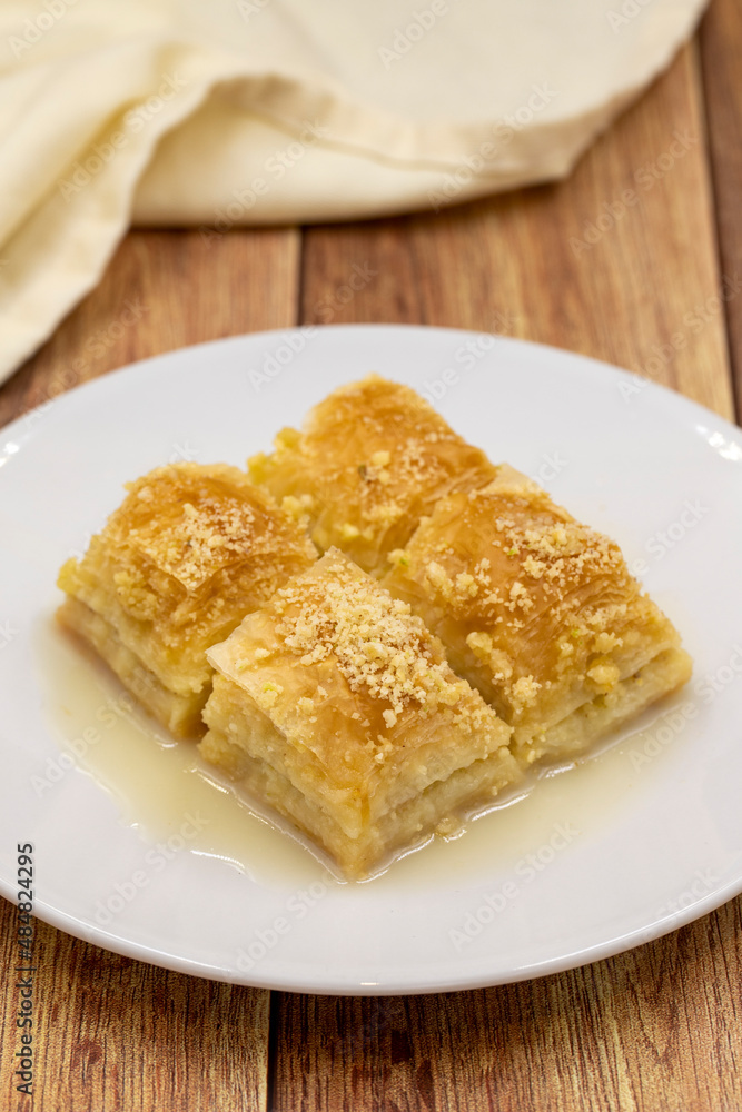 Baklava with milk (sutlu nuriye). Baklava with hazelnut and milk on a wooden background. Baklava with milk (sutlu nuriye). Baklava with hazelnut and milk on a wooden background.