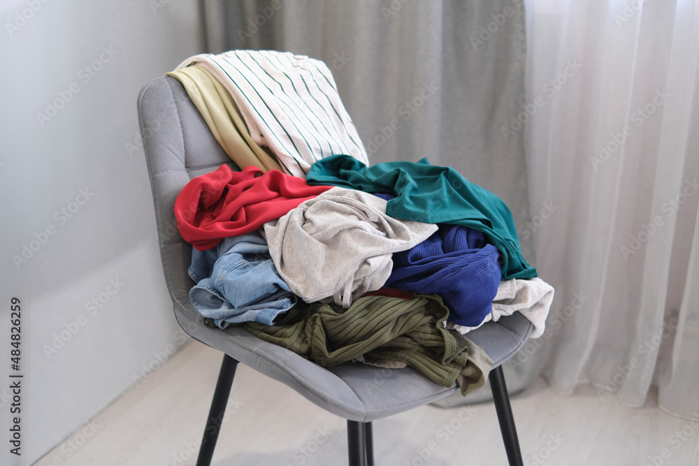 person throws used clothes on the chair. Pile clothes on chair. Heap of