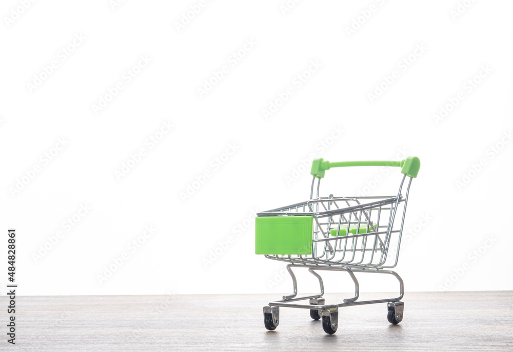 Isolated on white background, a small supermarket shopping cart for buying toys. Sell, buy, shopping mall, market, store, concept, and copy space are all words that come to mind while thinking about s