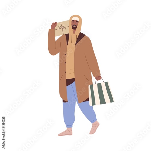 Happy man walking with holiday gift box and shopping bag. Guy going and carry...