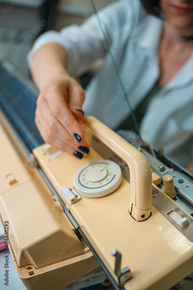 the person is engaged in knitting on a household knitting machine. handmade the person is engaged in knitting on a household knitting machine. handmade