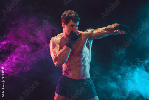 Half length of athlete boxer who training and practicing swing on smoke background. Sport concept