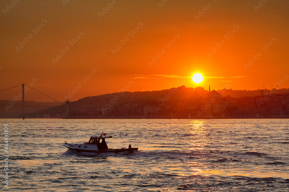 Obraz premium A small boat floats on the sea against the backdrop of the rising sun. Travel to Istanbul, Turkey.
