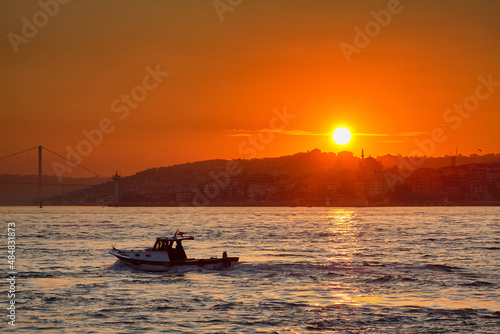 A small boat floats on the sea against the backdrop of the rising sun. Travel to Istanbul, Turkey.