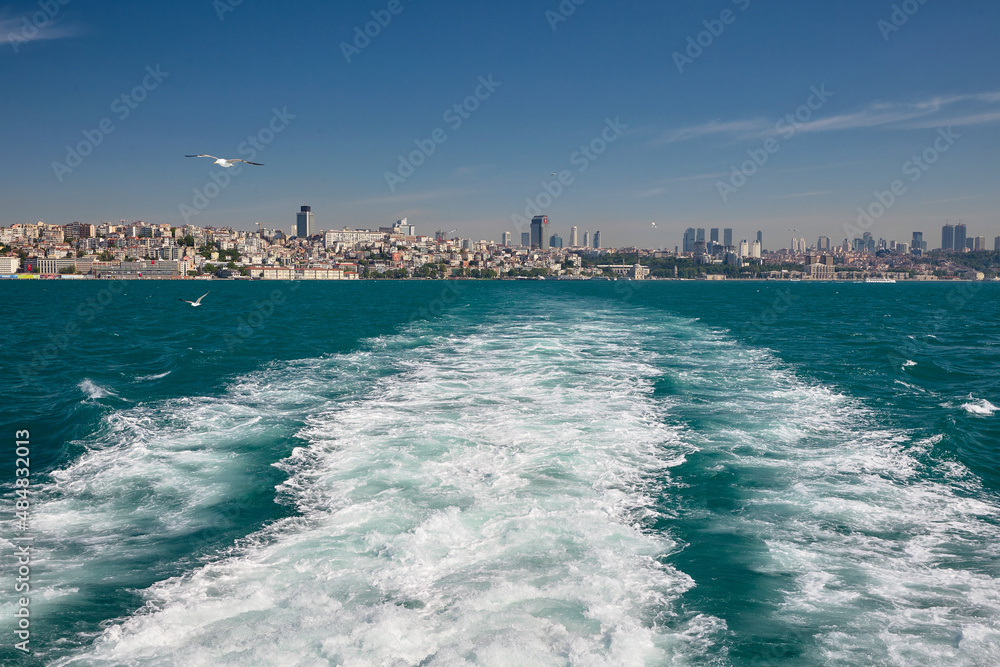 Seagulls fly over the sea behind the boat. Ships wake. The ship is leaving the big city. Journey to istanbul