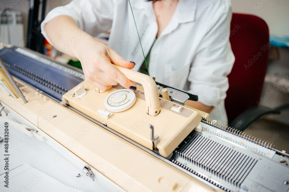 the person is engaged in knitting on a household knitting machine. handmade the person is engaged in knitting on a household knitting machine. handmade