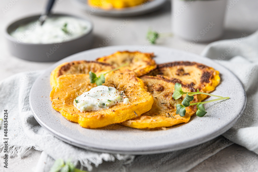 Fried patisson or yellow zucchini with sauce and micro greens, grey background. Fried patisson or yellow zucchini with sauce and micro greens, grey background.